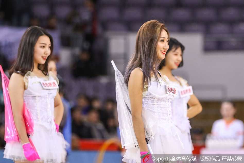 在比赛暂停的间隙，几位篮球宝贝正在场地中央进行热舞表演，她们的动作整齐划一，充满张力，身后巨大的记分牌和看台上密密麻麻的观众构成了她们最宏大的背景板。