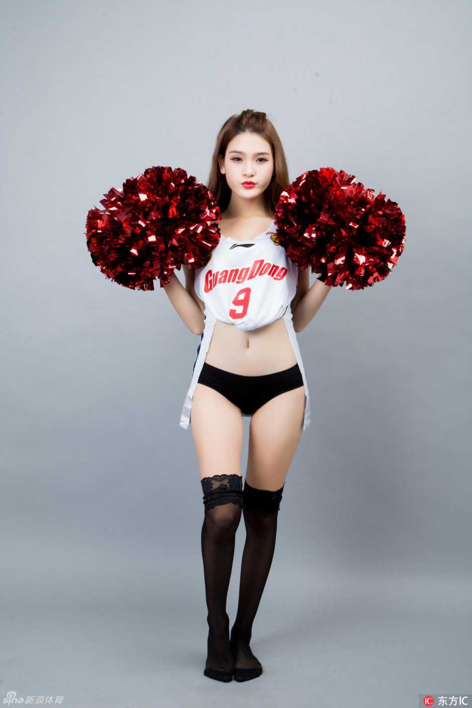 两位青春洋溢的篮球宝贝在赛场边相视而笑，她们扎着利落的马尾，身穿深色助威服，笑容如同春日阳光，试图融化新疆队带来的寒冷比分。