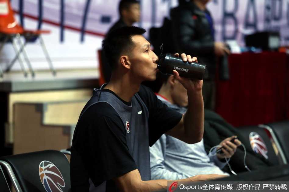 易建联在三分线外运球调整一步后干拔跳投，出手点极高，防守球员只能望球兴叹。背景中，队友们正在积极拼抢篮板位置。