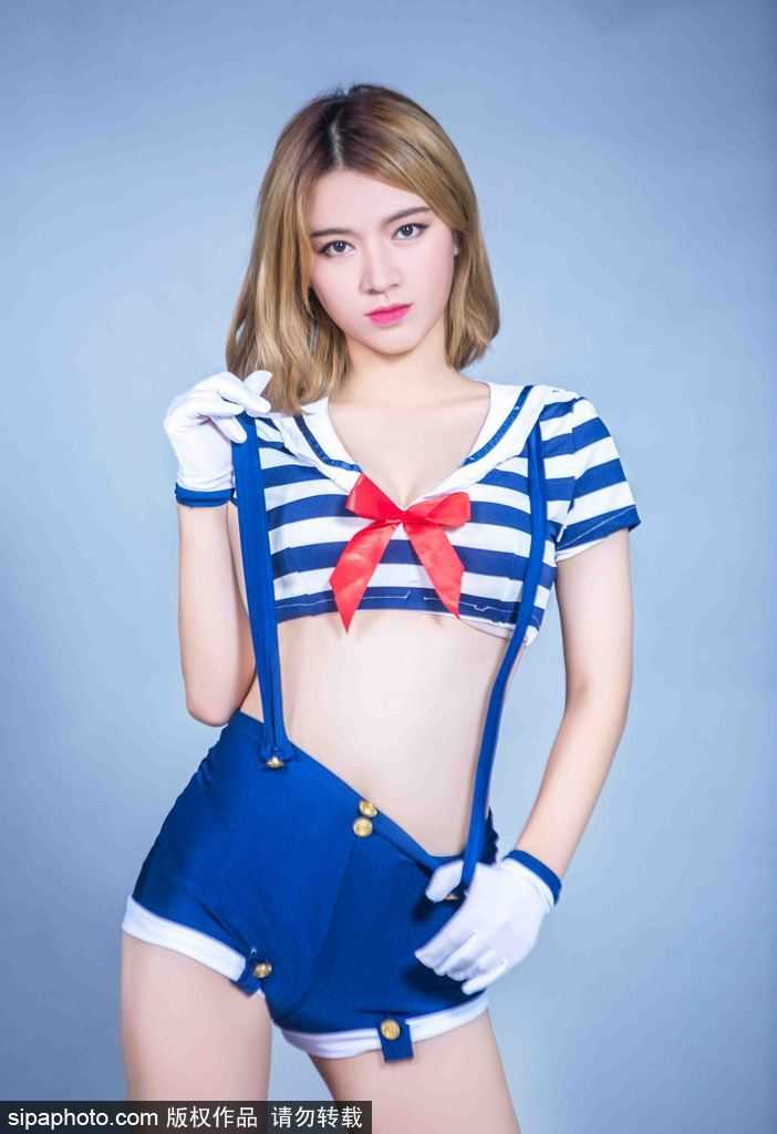 一名宝贝单手叉腰，侧身而立，水手服的短裙衬托出修长美腿，背景的柔光模糊了场馆的硬朗，只留下属于舞时尚的柔美与坚定。