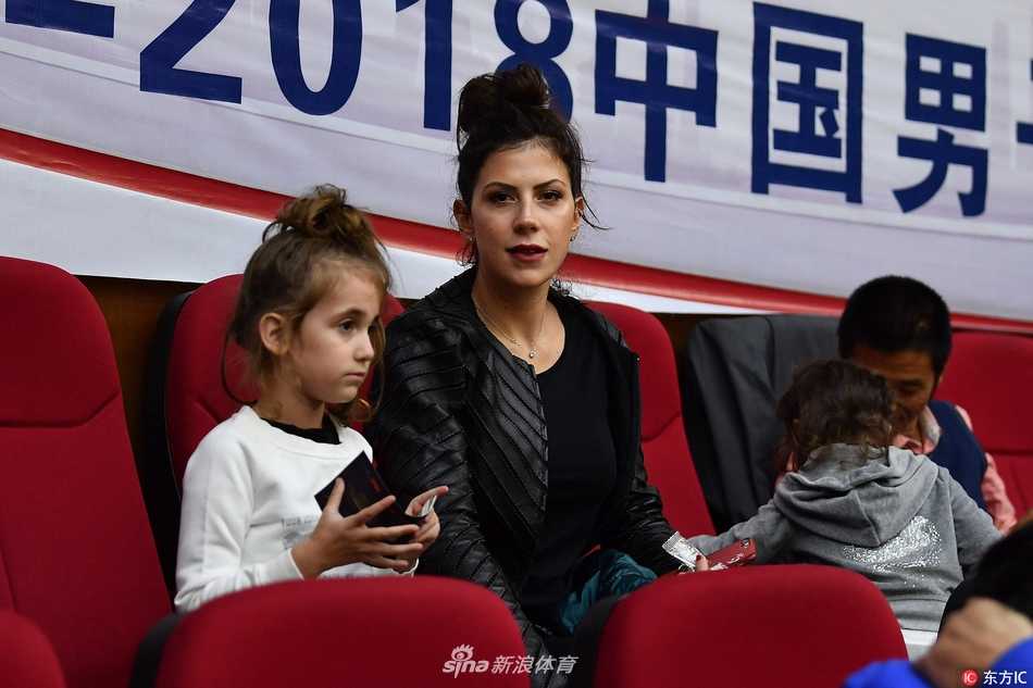 博洛西斯金发碧眼的妻子抱着年幼的女儿坐在看台上，两人的目光紧紧追随着场内正在热身的丈夫与父亲，眼神中满是跨越重洋的支持与爱意。