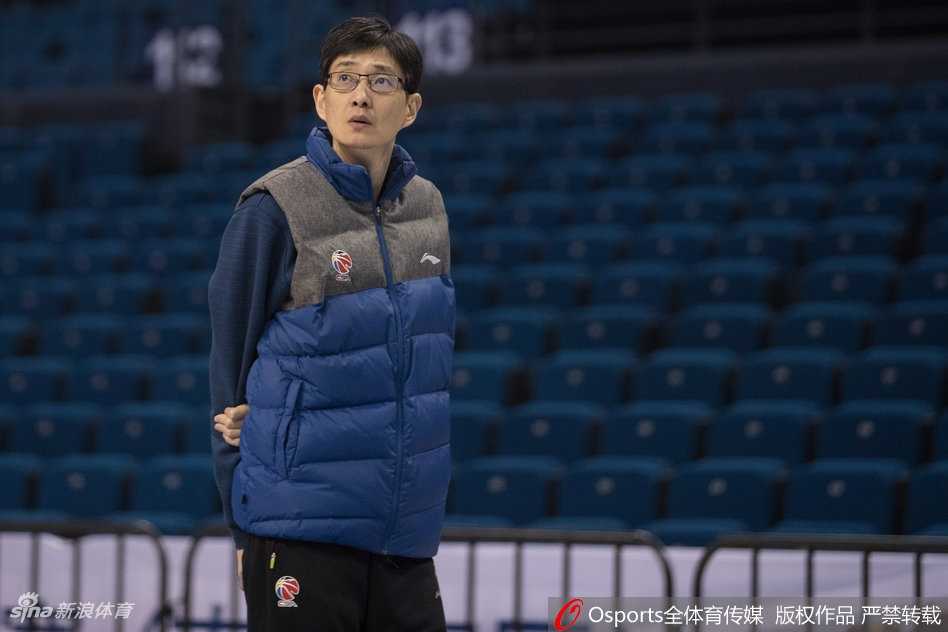 体能教练正蹲在地上为一名喘着粗气的内线球员压腿放松，球员脸上的汗珠清晰可见，展现了训练背后的艰辛付出。