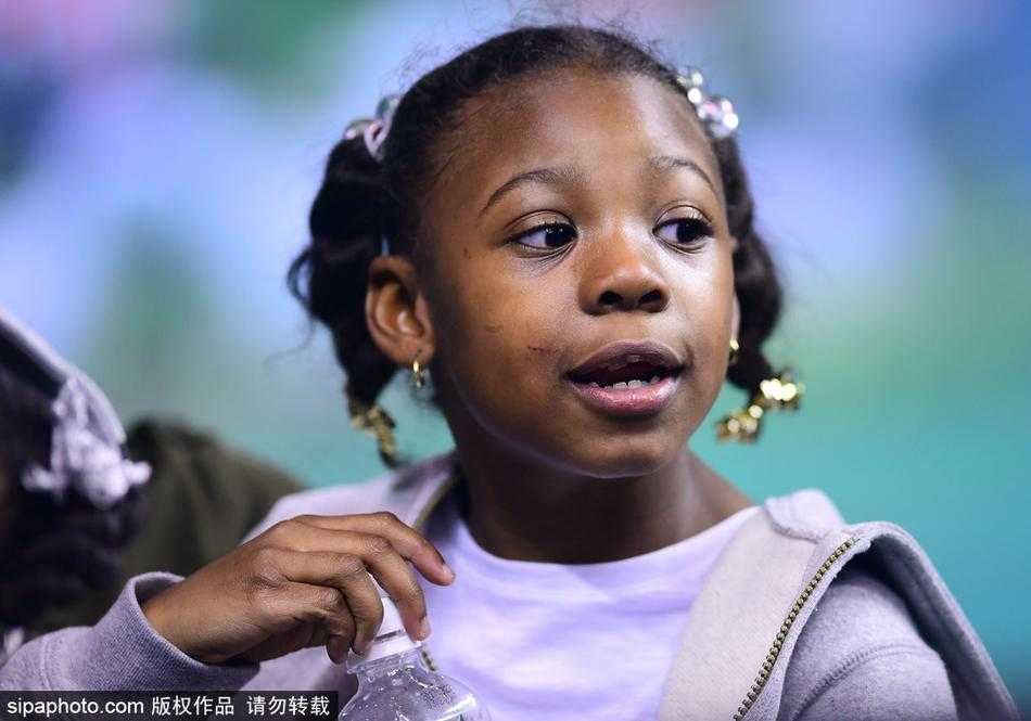 小女儿似乎有些困倦，小手托着腮帮子，但依然努力睁大眼睛望向场内，不想错过任何一秒爸爸在球场上的英姿。