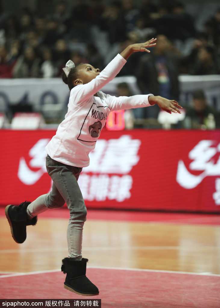 哈德森的大女儿坐在妈妈身边，微笑着注视妹妹在过道里拍球玩耍，眼神里满是宠溺，仿佛一个懂事的小监护人。