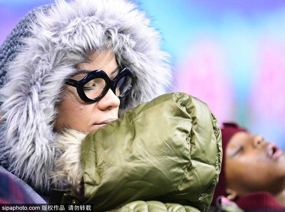 哈德森妻子面带微笑，眼神温柔地看着怀里的女儿。即使在嘈杂的体育场内，母女二人也自成一方宁静的小天地，仿佛时间都为此放缓了脚步。