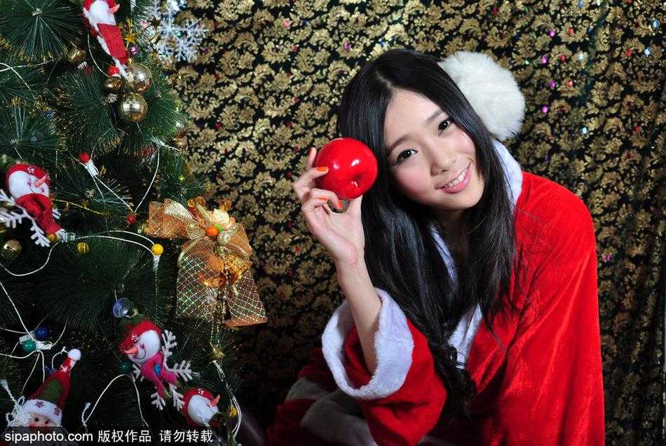 手捧红色圣诞袜的女孩在彩球点缀下回眸一笑，洋溢着节日的欢快气息