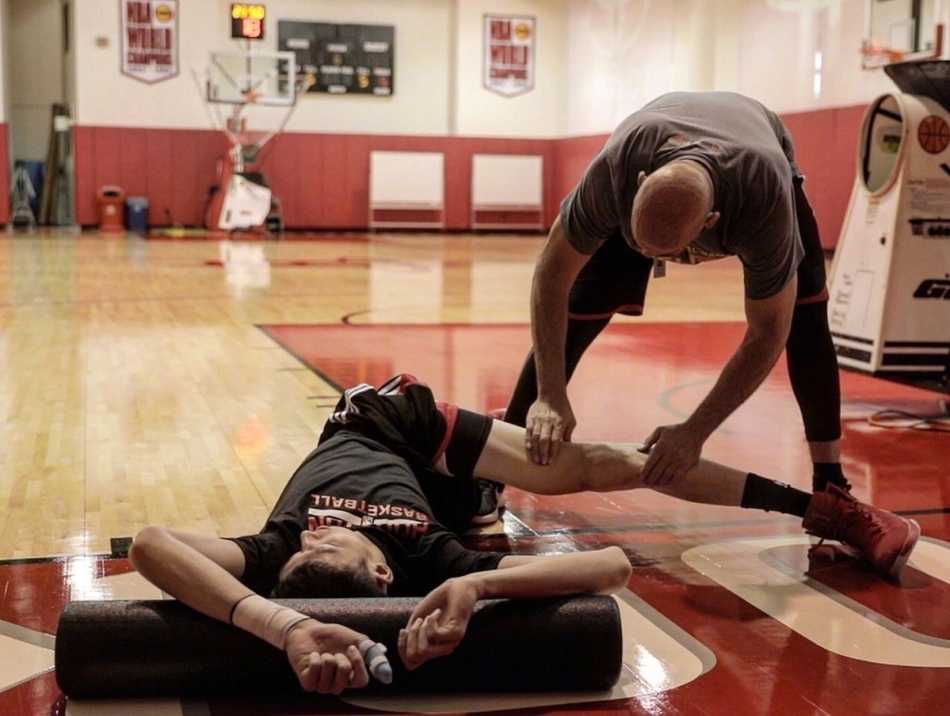 大魔王周琦在火箭队训练师的指导下挥汗如雨，尽管左手拇指的护具尚未摘下，但他眼神坚毅，在丰田中心的训练场上认真打磨每一个技术细节。
