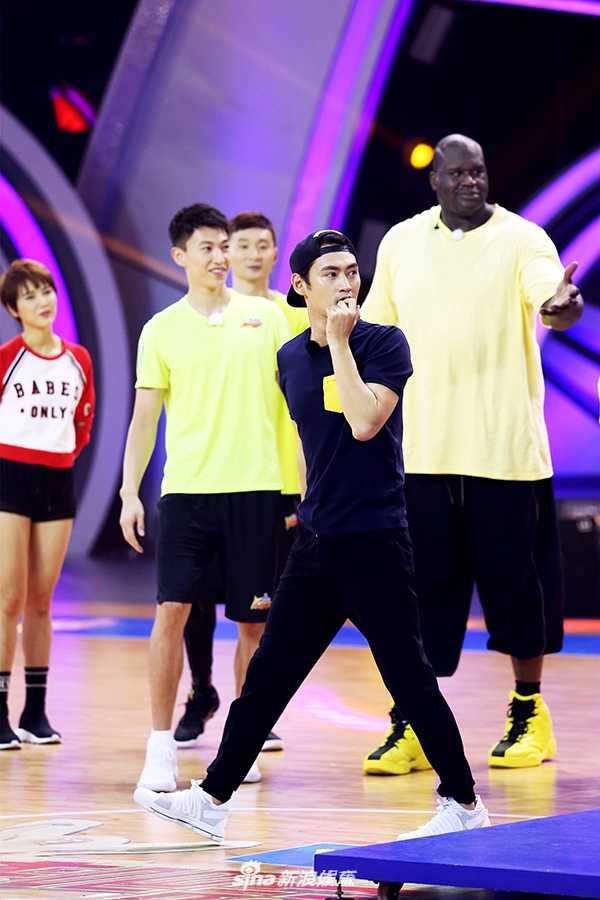 郑恺站在奥尼尔身边试图干扰其投篮，两人身高对比悬殊，但郑恺表情认真投入，画面充满竞技游戏的趣味