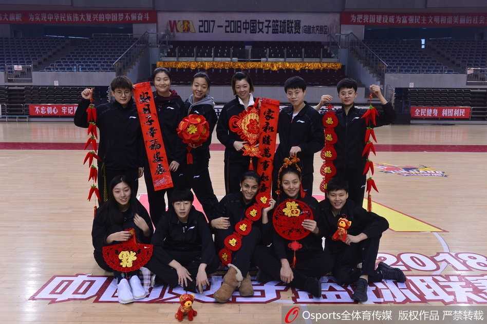 新疆女篮的队员们簇拥在一起，手持春联和福字，背景是喜庆的红色，姑娘们眼神清澈明亮，笑脸盈盈，定格了这支坚韧之师最柔情的瞬间。