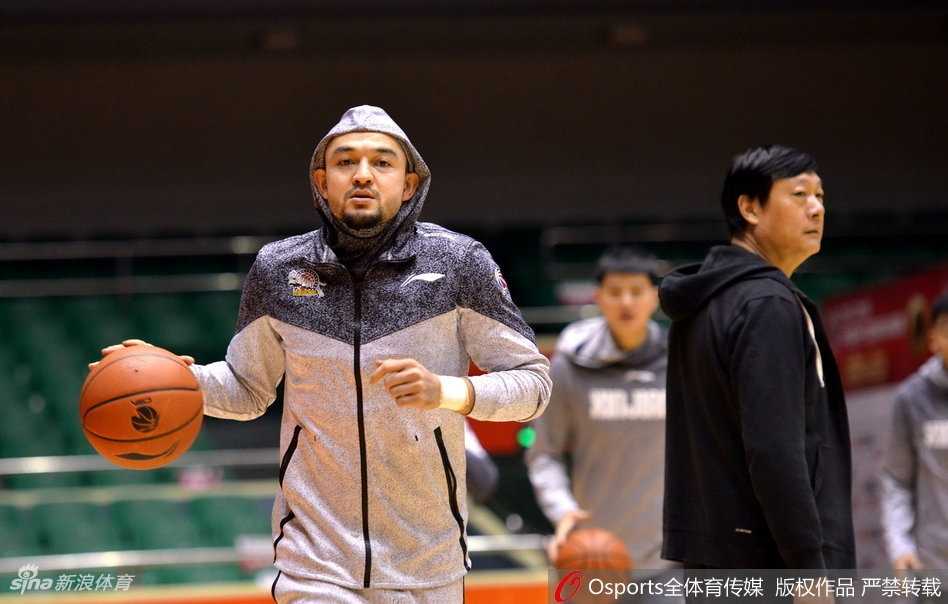 拉伸放松时刻，可兰白克坐在地板上，平静地望向远处，背景是空旷的球馆和队友模糊的身影，此刻的宁静预示着不久后即将在这里掀起的惊涛骇浪。