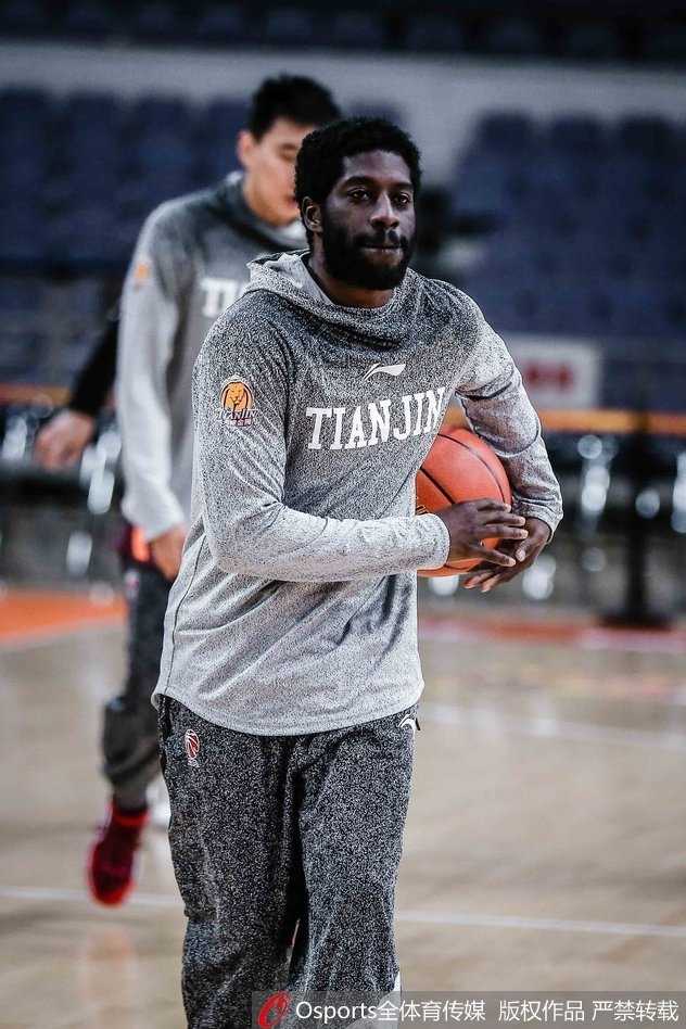 主教练手持战术板，神情严肃地为队员们讲解跑位路线，队员们认真倾听，眼神中充满对胜利的渴望。