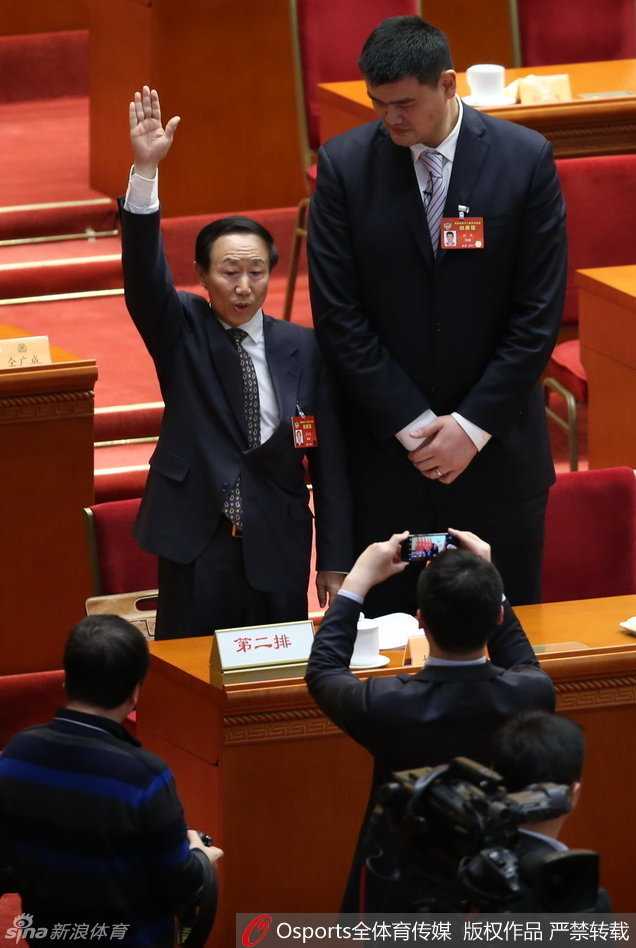 姚明政协发声:体育强国的根基在于群众的热爱与市场的沃土 姚明站在人民大会堂的会议厅内,正装笔挺,面带从容的微笑,标志性的身高让他即便在人群中也能被一眼认出,背景是庄严肃穆的会场环境,记录下这位体育人履职的珍贵瞬间。