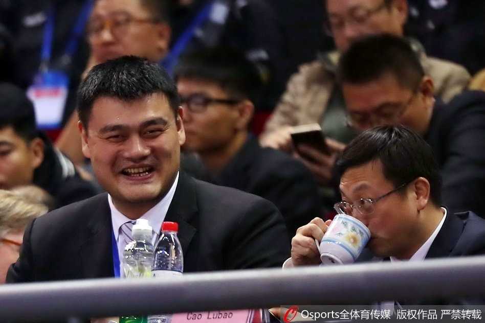 篮协主席姚明身着一件深色长款大衣，神情专注地站在场边观战，目光深邃而充满期待，仿佛在审视着红队这些年轻人的每一滴汗水与成长。