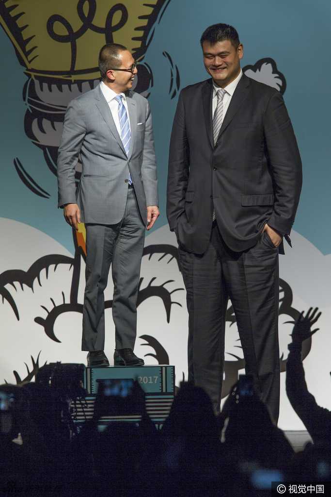 霍启刚与霍启山两兄弟并肩站在论坛背景板前，两人皆穿着正装气质儒雅，面对镜头露出谦逊而自信的笑容，展现出霍家第三代沉稳干练的风采。