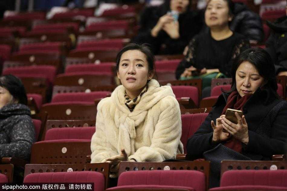 寒冬貂绒助威,辽宁本溪主场球迷彰显豪迈真情 赛场边,一对情侣球迷依偎而坐,两人身上华贵的貂绒在灯光下泛起柔和光泽,男生正指向场内的记分牌,脸上露出轻松的笑容。