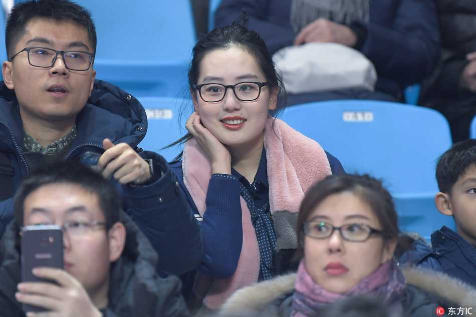 一位穿着白色毛领外套的年轻女性，面容清秀，坐在观众席前排，背景是模糊的赛场，她似乎正为吉林队错失的一次机会感到惋惜。