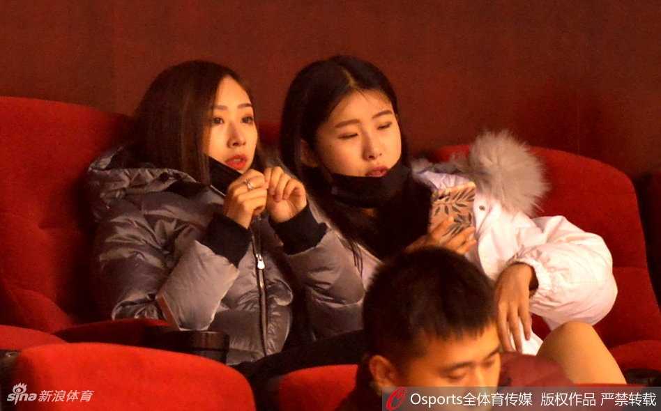 睢冉妻子在看台上露出灿烂笑容，似乎正用手机记录下这激动人心的比赛瞬间，而丁彦雨航女友则在一旁安静注视场内。