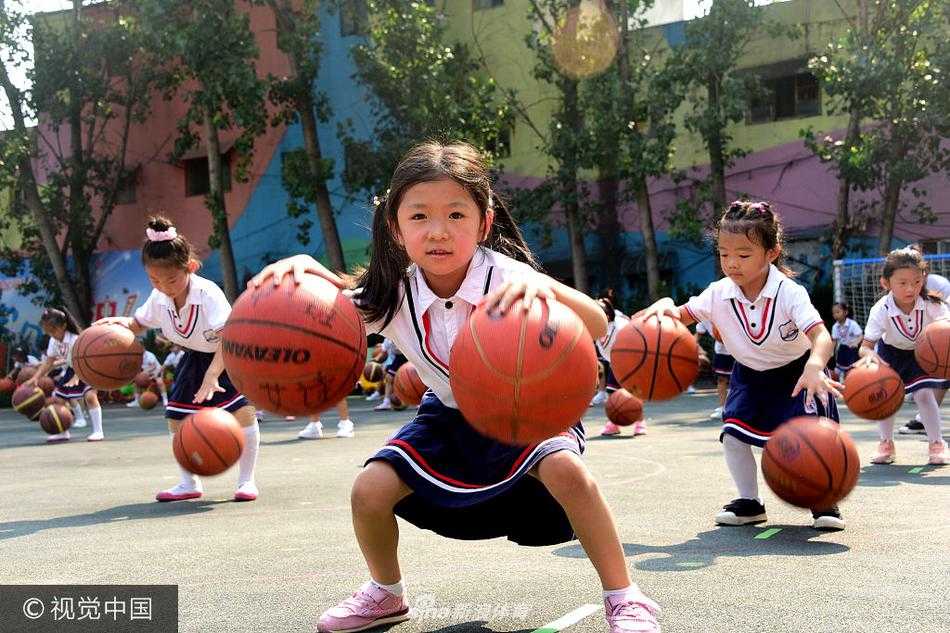 从高空俯瞰，操场上孩子们排列成整齐的方阵，手中的篮球同时跃起，仿佛一片律动的红色海洋，震撼的场面见证着幼儿体能教育的丰硕成果。