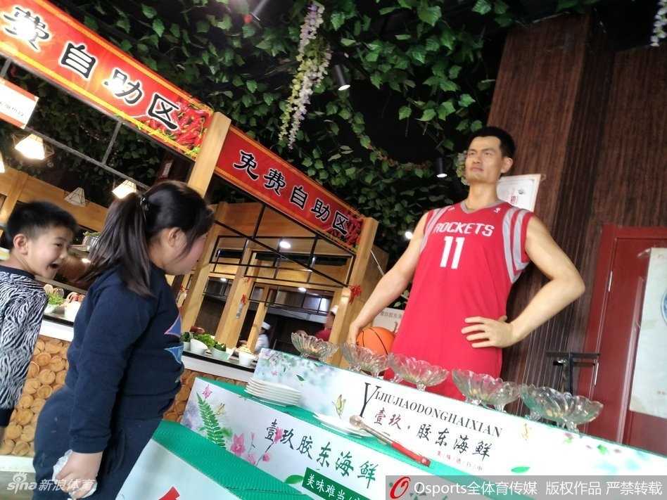 山东邹平饭店惊现“巨人”迎宾,姚明蜡像身穿火箭队服引围观 一位身形巨大的‘篮球巨星’蜡像,身穿红色火箭队战袍,安静地站在饭店大厅中央,周围食客纷纷侧目,仿佛在仰望真正的巨人