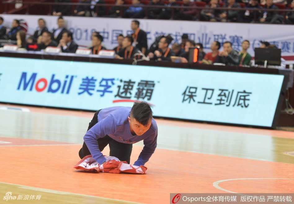 平凡英雄闪耀CBA赛场 擦地哥孟飞与他的篮球追梦之旅 在聚光灯下,孟飞双膝跪地,用力而专注地擦拭着木地板上的汗渍,他的动作敏捷而有力,与身后静止的广告牌和紧张的比赛氛围形成鲜明对比