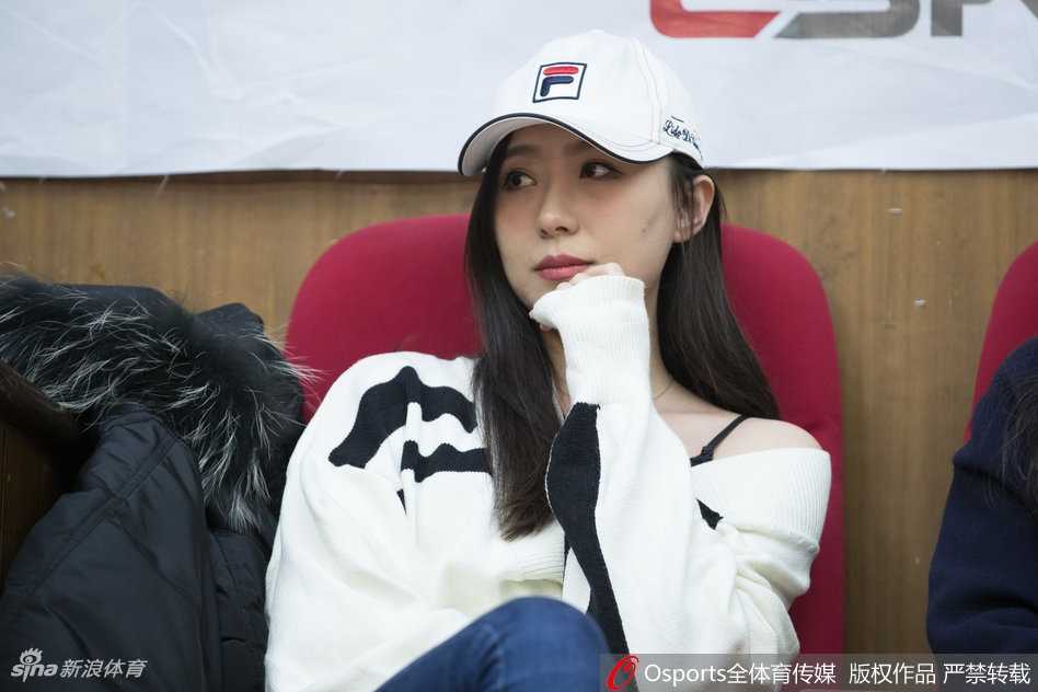 镜头拉近，这位美女的正脸更加惊艳。她肌肤胜雪，妆容精致却不浓艳，一双明亮的眸子在球场灯光的映照下仿佛藏着星辰。她双手轻轻托着下巴，即便是在喧闹的人群中，也自有一股恬静优雅的独特气质，让人忍不住多看几眼。