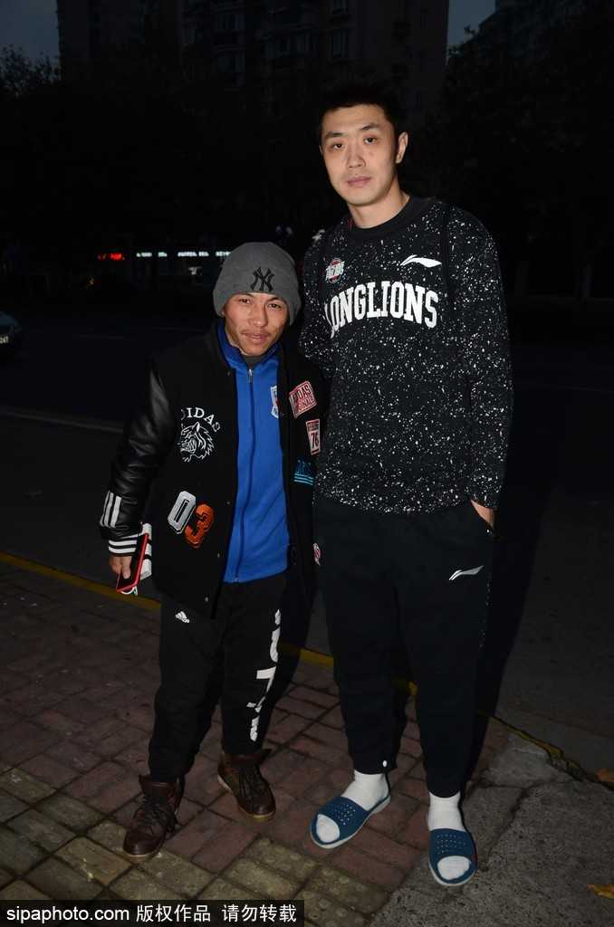 克里斯顿一手拖着行李箱，一手与球迷击掌，脸上洋溢着惊喜的笑容