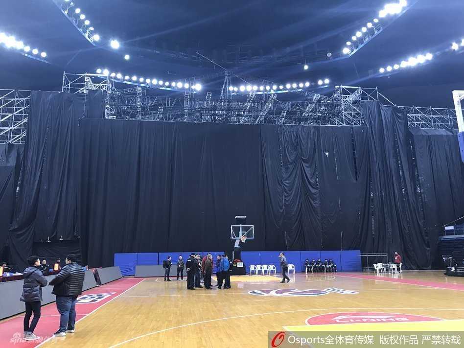 当篮球架遇见演唱会舞台:一场因“跨界”而取消的CBA比赛 从高处俯瞰体育馆内场,演唱会舞台的规模几乎占据了半片看台区域,舞台边缘与篮球场的三分线距离极近,场边的广告牌显得微不足道,整个空间显得拥挤而错乱。