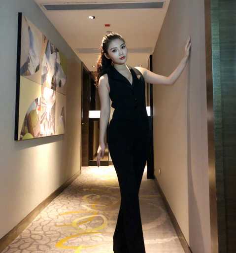 在一组创意写真中，徐冬冬模仿橱窗模特的姿态静静站立，她身穿淡粉色修身针织衫与棕色长裤，显得温婉干练。紧身衣物完美贴合她的身体曲线，展现出健康而饱满的体态，与身旁略显单薄的假模特构成一幅有趣又充满视觉冲击力的画面。