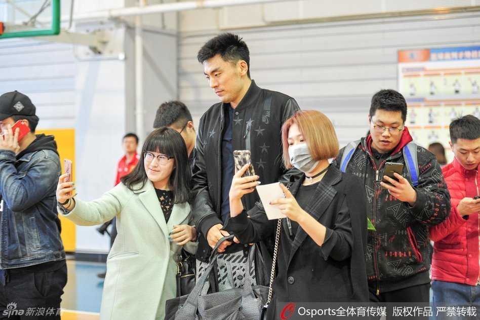 一位小球迷在训练馆外偶遇李晓旭，眼神中满是崇拜与关切，李晓旭略显疲惫但依然俯身满足他的合影愿望。