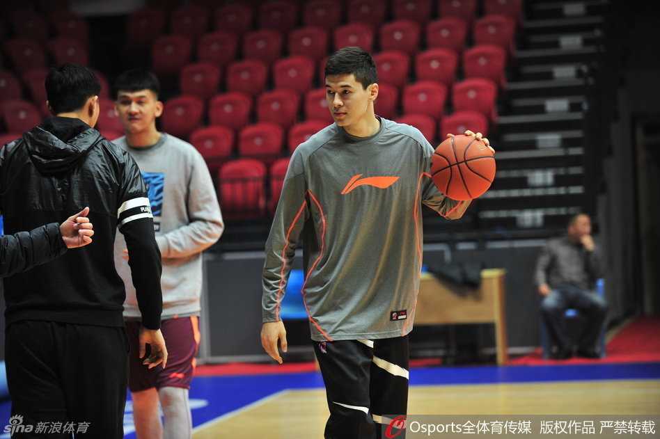 队长阿不都沙拉木与队友李根在训练间隙认真探讨战术配合，两人用手比划着跑位路线，神情专注。