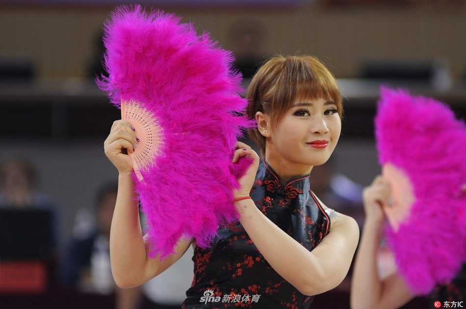 金色的扇面在姑娘们手中整齐开合，宛如赛场边绽放的簇簇金花，她们自信的笑容与旗袍的典雅相映生辉，为激烈的对抗增添了几分柔美与从容。