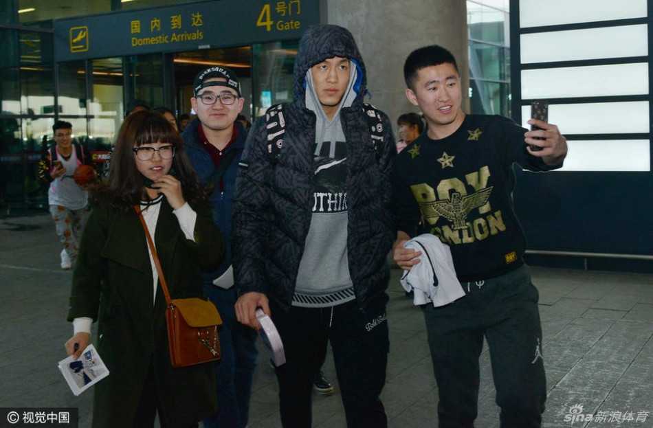 无论成败与辽同在:辽篮将士载誉归乡,真情瞬间温暖寒冬 身穿黑色长款羽绒服的郭艾伦神态亲和,微微弯腰俯身,正在为一位身着蓝色辽篮球衣的小球迷认真地签名,周围是无数高举手机记录这一刻的热情人群。