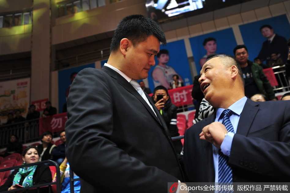 姚明和兰德里并排站在一起，两人都穿着正装，姚明双手交叉在前，兰德里则双手背后，他们面对镜头，神情轻松愉快，如同老友聚会。