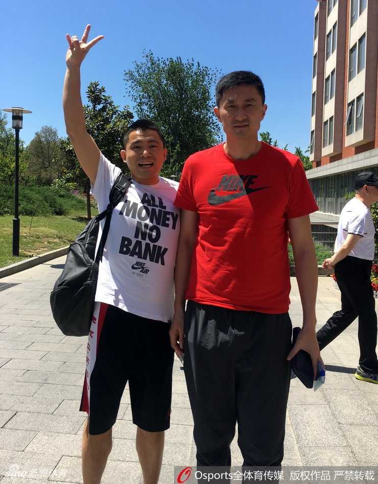 主教练杜锋面带微笑，亲切地与热情的球迷们站在一起合影，现场氛围轻松愉快。