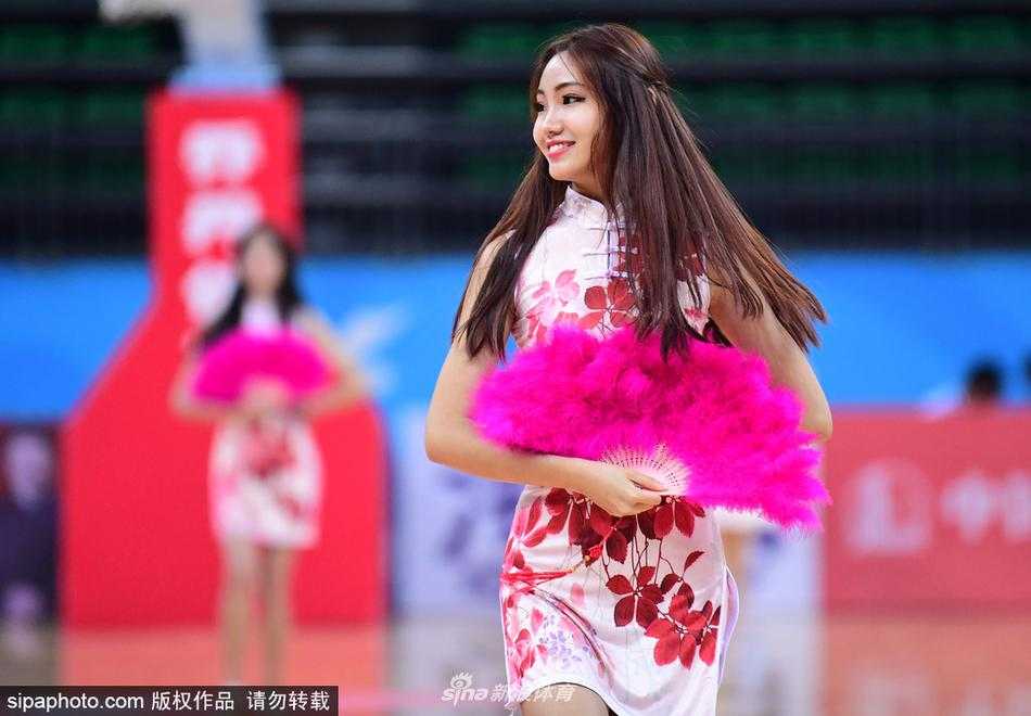 津门旗袍宝贝舞动全运赛场 篮球架起传统文化与体育桥梁 在球场炫目的灯光下,旗袍宝贝们整齐划一地扬起手中金色的花球,她们身上的旗袍颜色鲜艳,红色与金色交织出喜庆热烈的赛场氛围。