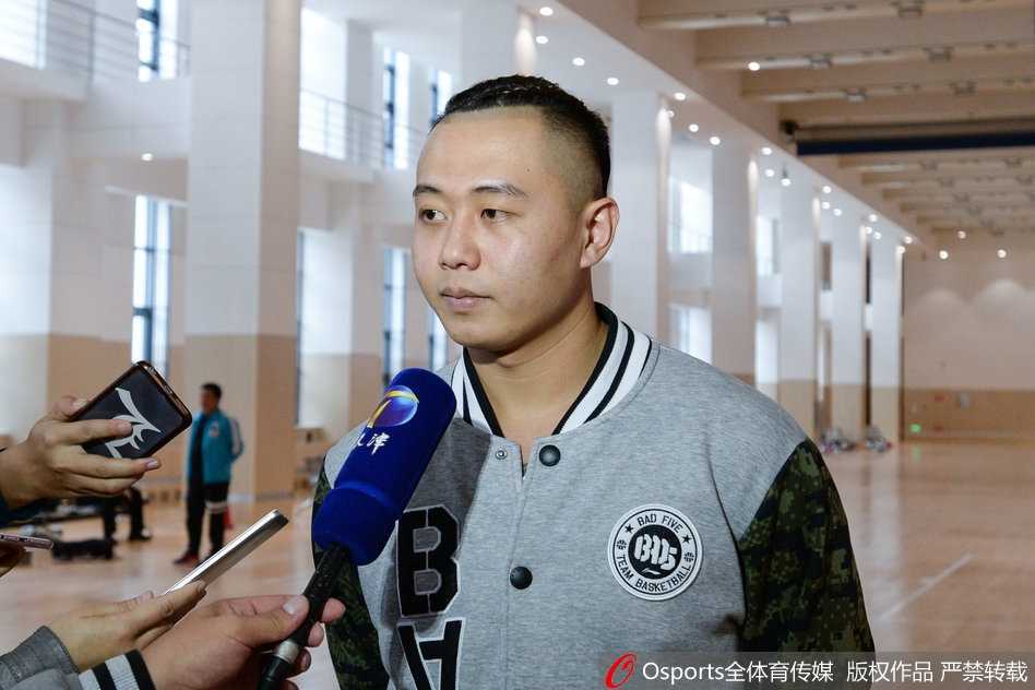 主教练徐贵军被球员们簇拥着看向镜头，他脸上挂着慈祥又略带腼腆的笑容，平日训练场上的严厉此刻化作了与弟子们同乐的温情，画面充满了人情味。