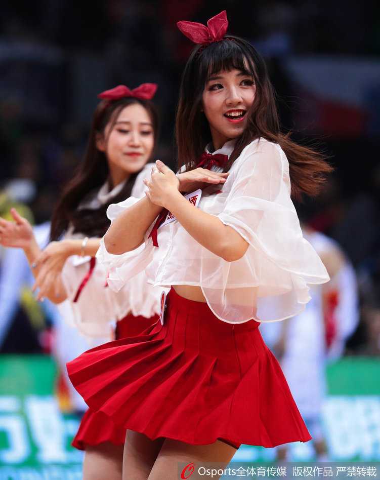 深圳篮球宝贝烈焰红裙舞动赛场 助力新世纪大胜青岛双星 集体造型中,宝贝们错落有致地摆出优美姿态,红色的裙装在灯光下格外耀眼,她们的身姿与手中的花球构成一幅充满美感的画面。
