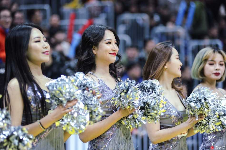 侧后方视角记录下宝贝们队形变换的精彩瞬间，她们手中的手杖整齐划一地指向天空，在体育馆绚烂的灯光下，宛如一片闪闪发光的魔法森林。