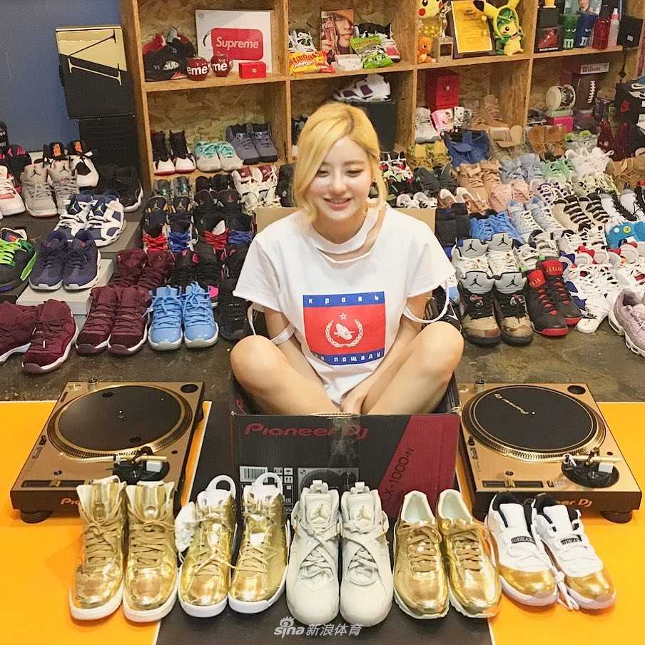 球鞋女神DJ Soda:从打碟台到鞋墙,她的Air Jordan帝国 DJ Soda 半蹲在地上,身后是堆积如山的Nike与Jordan鞋盒,她穿着一袭白色连衣裙,金色的短发显得格外俏皮,眼神中透露出对自己收藏帝国的满足与骄傲。