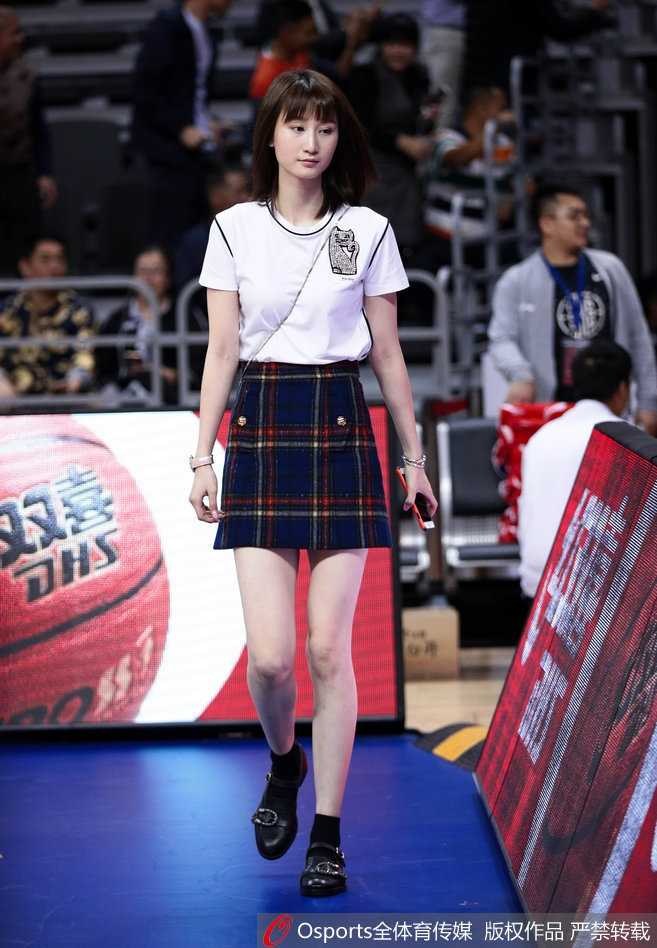 比赛暂停间隙，镜头扫过场边贵宾席，周鹏妻子与友人低头私语，脸上洋溢着自豪的神情，身后巨大的广东队徽标格外醒目