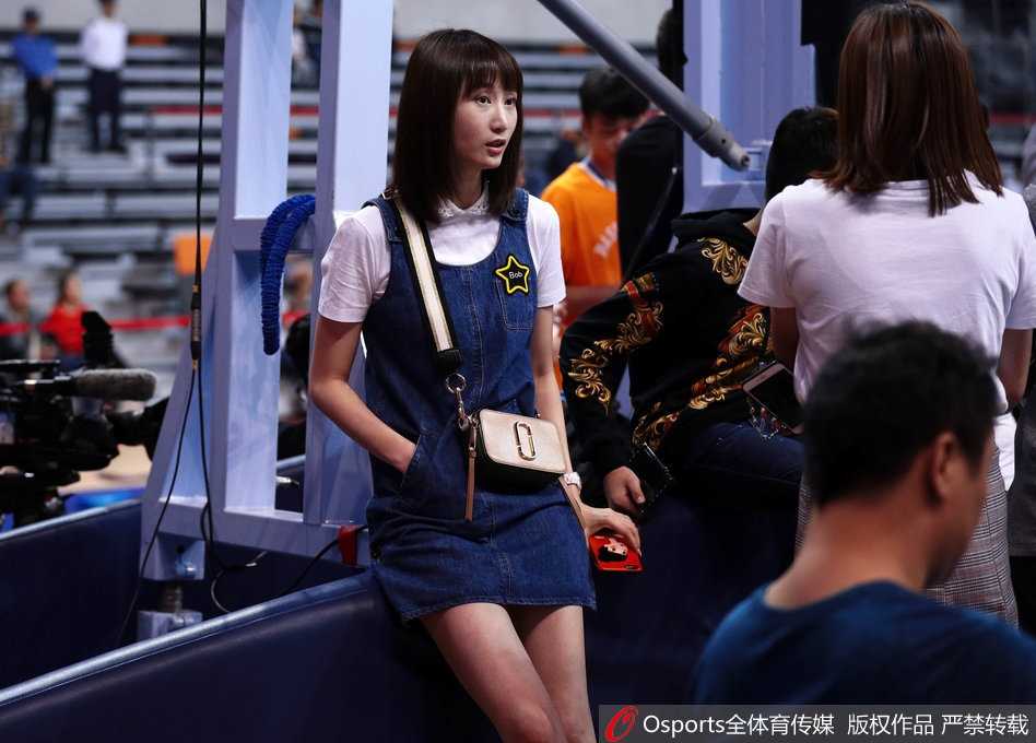 刘美在比赛暂停间隙轻轻拨弄长发，眼神不经意间掠过镜头，既有少女般的灵动，又有成熟女性的从容。这条牛仔裙与她188厘米的身高相得益彰，让她在场边人群中脱颖而出。