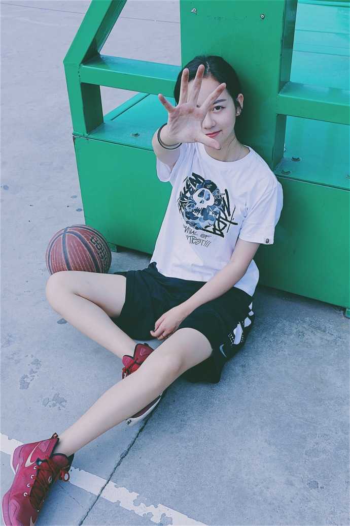 孙夕雨身着白色骑士队T恤，双手叉腰站在街头篮球场边，阳光洒在她身上，甜美的气质中透着一股不服输的劲头。
