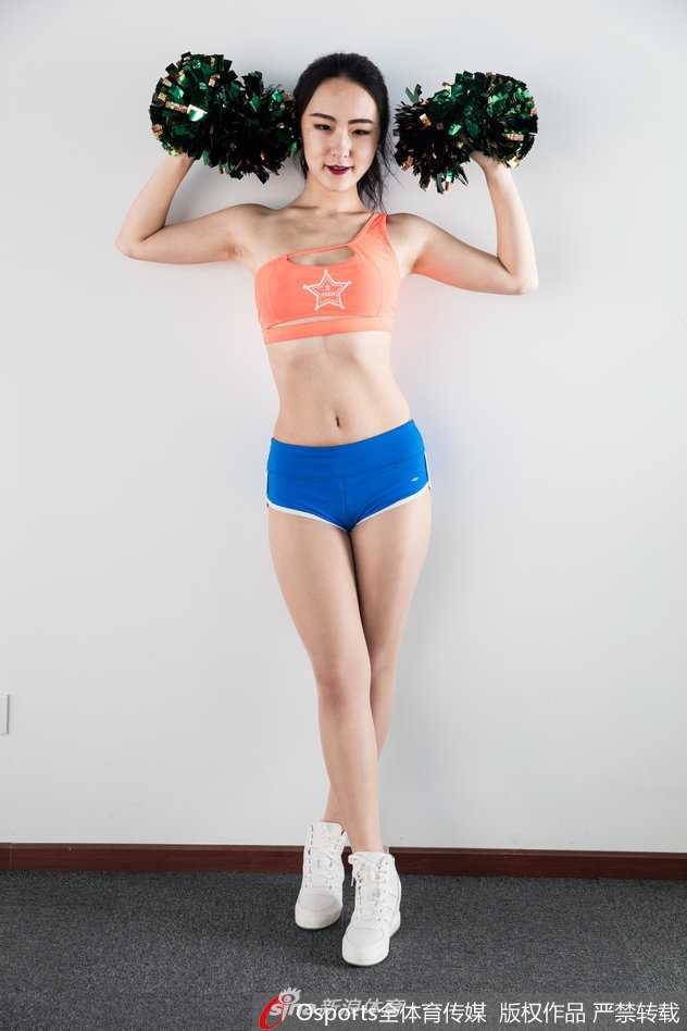 XTM啦啦队成员双手紧抱篮球，马甲线清晰可见，阳光洒在健康的小麦色肌肤上，眼神中透露出对赛场瞬间的专注与热情。