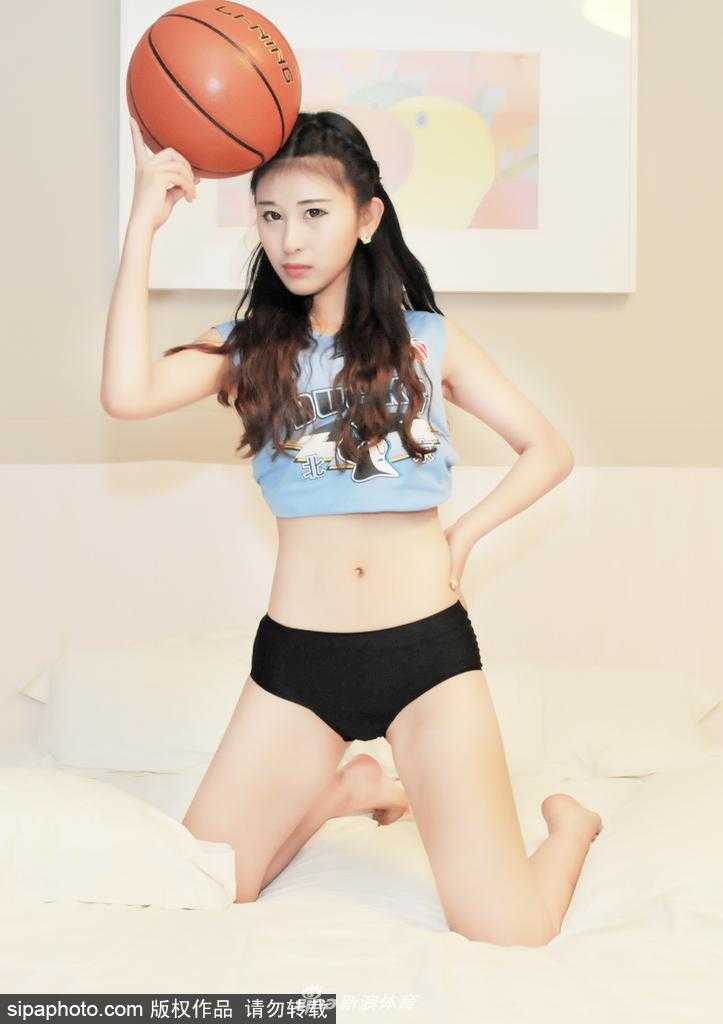 篮球宝贝在床边摆出俏皮的姿势，纤长的美腿和可爱的神态透露出属于年轻人的青春活力，仿佛在为首钢队注入元气