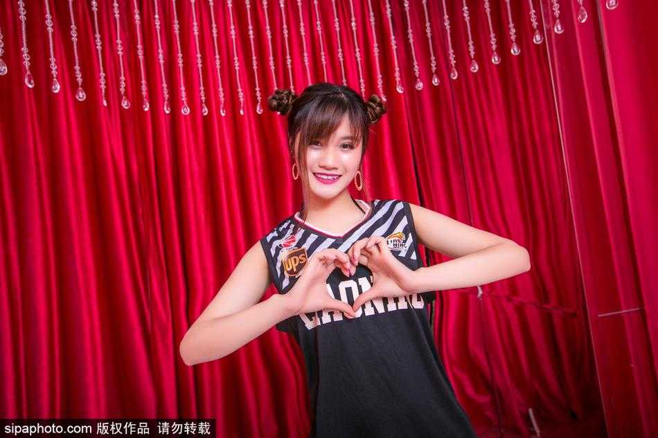 镜头拉近，这位篮球宝贝的笑容极具感染力，头上的哪吒小鬏鬏显得俏皮又精神，仿佛脚踩风火轮在为场上的辽篮将士加速。