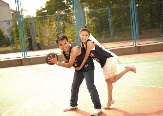 篮球架下的白纱与球衣,这才是爱情最热血的模样 新郎从背后温柔环抱坐在罚球线上的新娘,两人手中共同托举着一颗篮球,背景的篮球架和看台都成了他们纯粹爱情的沉默见证者。