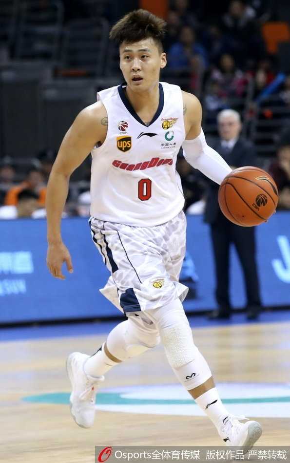 青岛队外援吉布森在易建联的长臂干扰下强行突破上篮，尽管身体失去平衡，他依然奋力将球抛出，眼神中透露出不甘与顽强。