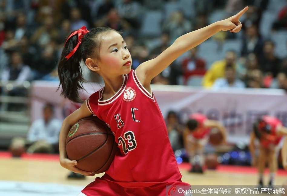 身穿红色球衣的小球员在赛场上高高跃起，用胸部优雅地停下高空球，目光坚定地观察着场上局势，宛如一位少年指挥官。