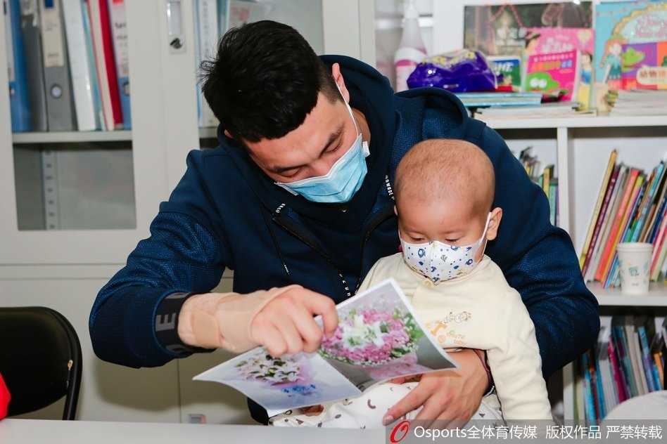 翟晓川张松涛与白血病儿童共绘温暖篮球梦 张松涛弯腰将一个大号的霹雳鸭玩偶递给坐在病床上的小朋友,小朋友双手伸出准备接过礼物,眼睛里闪烁着惊喜与兴奋的光芒,旁边病床上的家长也露出了欣慰的笑容