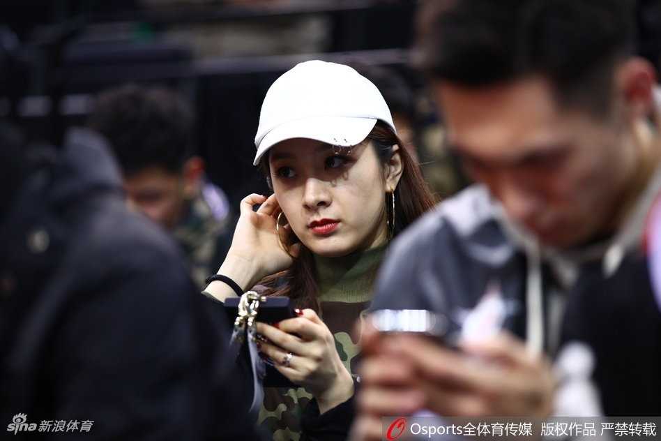 杨思雨侧身面对镜头，嘴角带着浅浅的笑意，翟晓川则凝视着赛场方向，两人沉浸在全明星周末的欢快氛围中，身后是座无虚席的热烈球场。